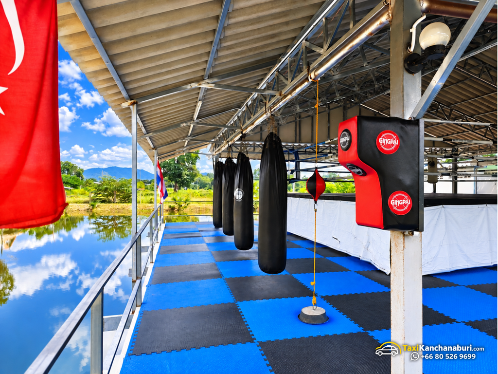 Muay Thai punching bags and training equipment beside the Thai flag at White Wolf Muay Thai Academy in Kanchanaburi